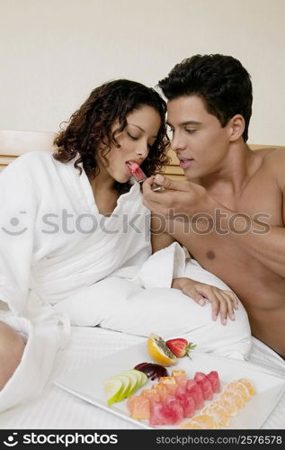 Close-up of a young man feeding watermelon to a teenage girl