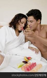 Close-up of a young man feeding watermelon to a teenage girl