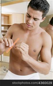 Close-up of a young man filing his nails in the bathroom