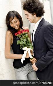 Close-up of a young man giving a bouquet of roses to a young woman