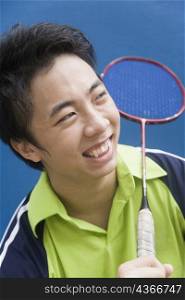 Close-up of a young man holding a badminton racket and smiling
