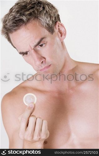 Close-up of a young man holding a condom
