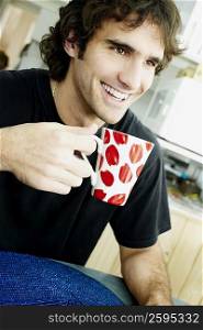 Close-up of a young man holding a cup of tea and smiling