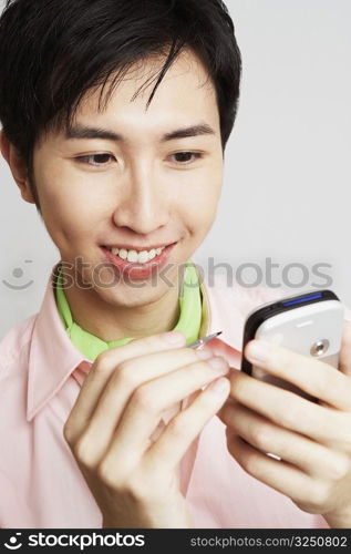 Close-up of a young man holding a digitized pen and a mobile phone