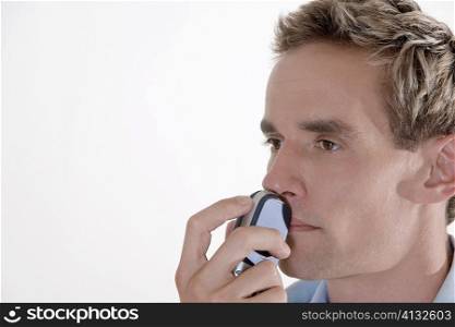 Close-up of a young man holding a mobile phone over his mouth