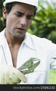 Close-up of a young man holding a pair of pliers