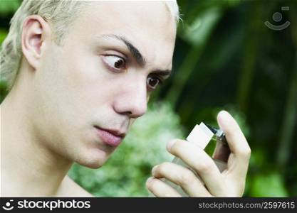 Close-up of a young man holding a perfume sprayer
