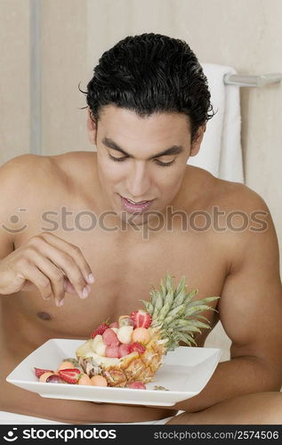 Close-up of a young man holding a plate of fruit