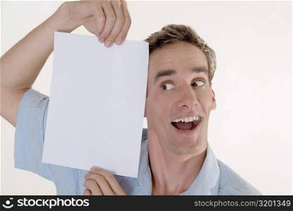 Close-up of a young man holding a sheet of blank paper