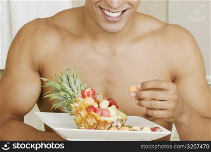 Close-up of a young man holding a tray of fruit salad