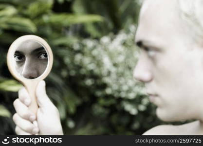 Close-up of a young man holding a vanity mirror