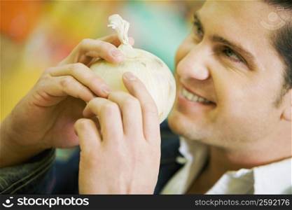 Close-up of a young man holding a white onion and smiling