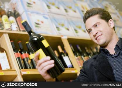 Close-up of a young man holding a wine bottle in a liquor store