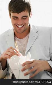 Close-up of a young man holding chopsticks and smiling