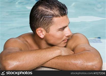 Close-up of a young man leaning at the edge of a swimming pool