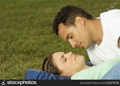 Close-up of a young man leaning over a young woman on the lawn