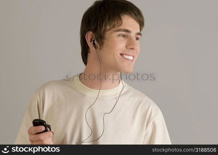 Close-up of a young man listening to an MP3 player and smiling