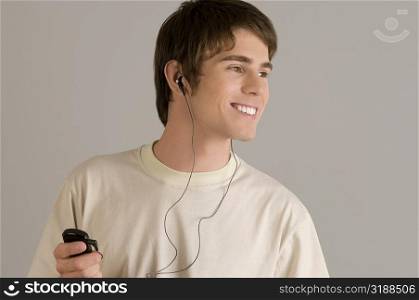 Close-up of a young man listening to an MP3 player and smiling