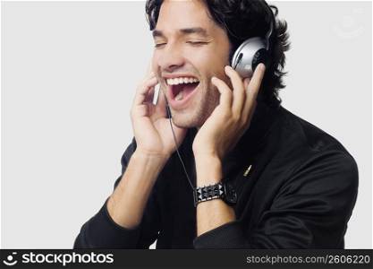 Close-up of a young man listening to music and laughing