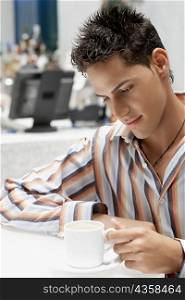 Close-up of a young man looking at a coffee cup