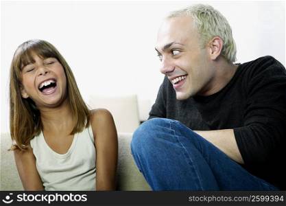 Close-up of a young man looking at a girl laughing and sitting on a couch