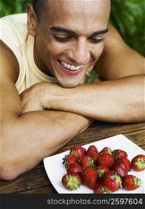 Close-up of a young man looking at a plate of strawberries and smiling