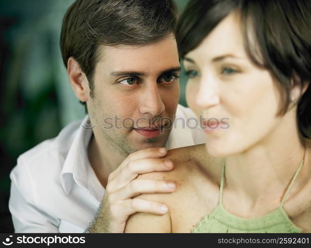 Close-up of a young man looking at a young woman with his hand on her shoulder