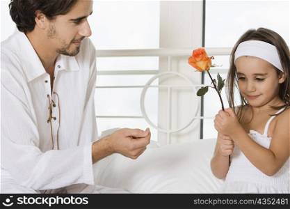 Close-up of a young man looking at his daughter holding a flower