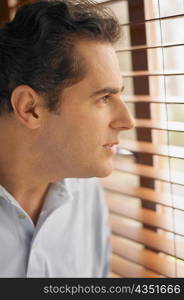 Close-up of a young man looking out of a window