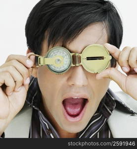 Close-up of a young man looking through a compass