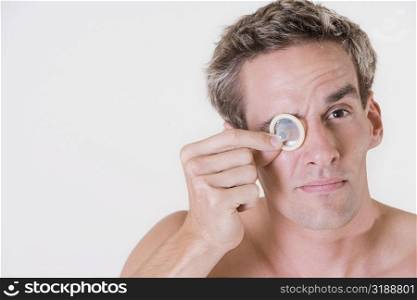 Close-up of a young man looking through a condom