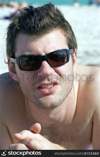 Close-up of a young man lying on the beach with his hands clasped, South Beach, Miami, Florida, USA
