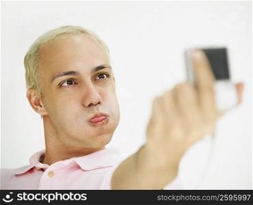 Close-up of a young man making a face and taking a self portrait with a digital camera
