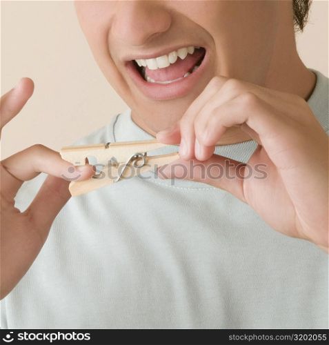 Close-up of a young man pinching his finger with a clothespin