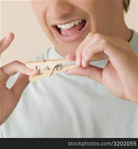 Close-up of a young man pinching his finger with a clothespin