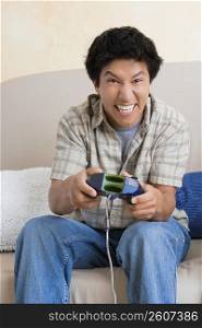 Close-up of a young man playing video game and smiling