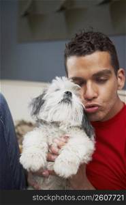 Close-up of a young man puckering his lips and playing with a dog