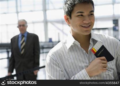 Close-up of a young man putting a passport with an airplane ticket in his shirt&acute;s pocket