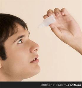 Close-up of a young man putting eye drops in his eyes