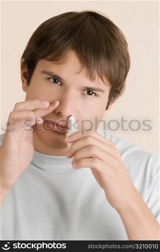 Close-up of a young man putting nasal spray drops in his nose