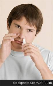 Close-up of a young man putting nasal spray drops in his nose