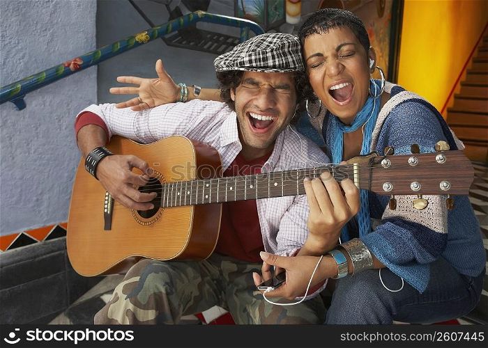 Close-up of a young man singing with a young woman and playing a guitar
