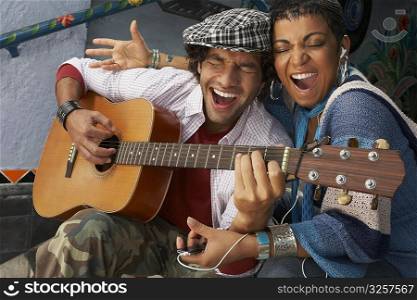 Close-up of a young man singing with a young woman and playing a guitar