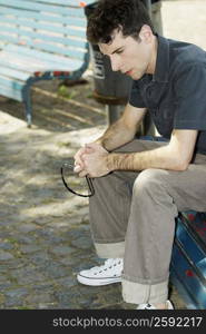 Close-up of a young man sitting on a bench