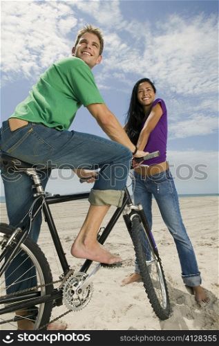 Close-up of a young man sitting on a bicycle with a young woman beside him