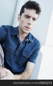 Close-up of a young man sitting with his hands on his knees