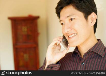 Close-up of a young man smiling and talking on a mobile phone