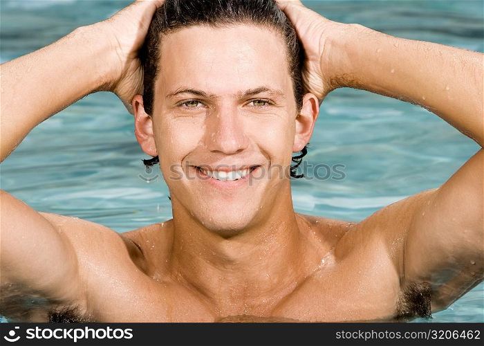 Close-up of a young man smiling with his hands behind his head in a swimming pool