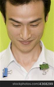Close-up of a young man smiling with paper clips on his shirt