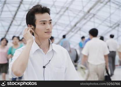 Close-up of a young man standing in a corridor and listening to music